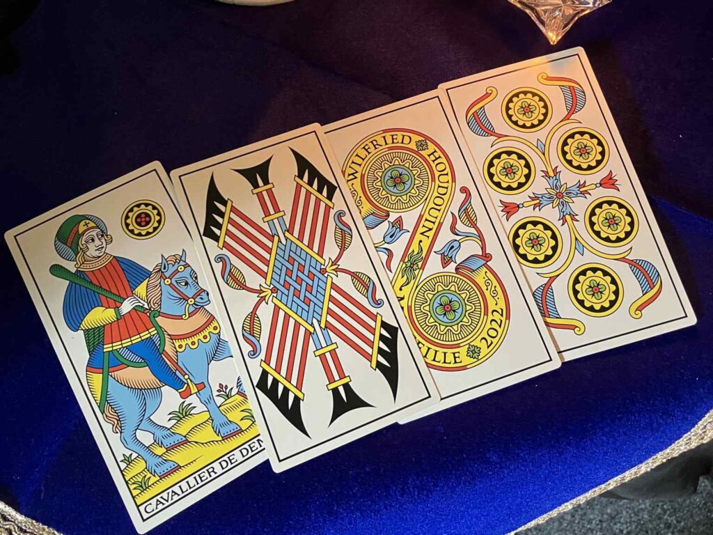 four tarot cards from the millennium edition marseille tarot on a blue velvet cloth