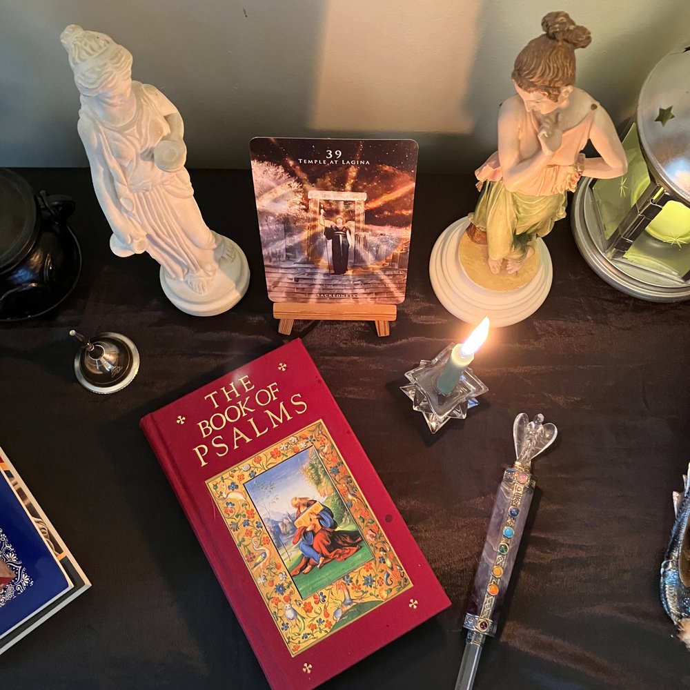My devotional altar with the Book of Psalms, the Temple at Lagina oracle card, Hekate statue, lit candle and prayer tools during my daily Psalm magic practice.